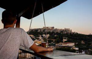 The great atmosphere, other travelers and the view to Acropolis is what you will feel at Pella Inn's Rooftop Bar.